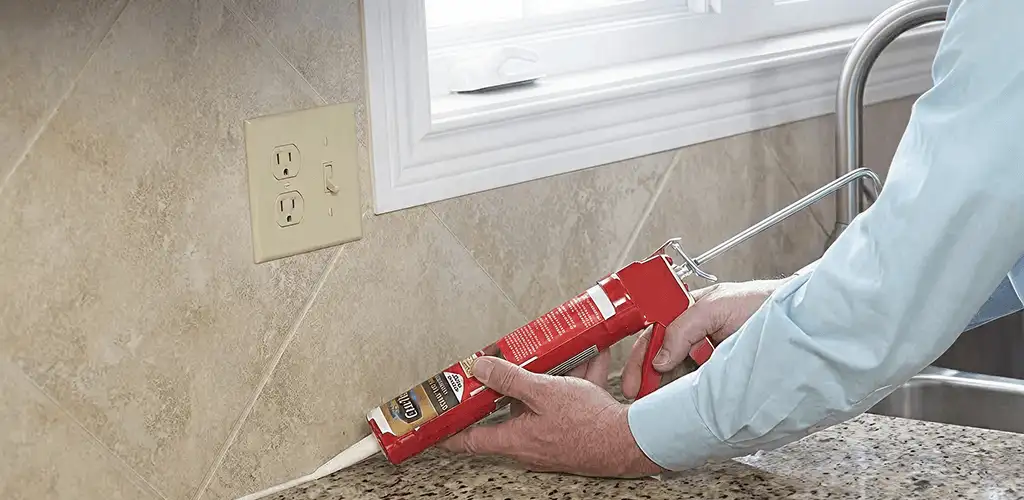 Handyman applying caulk along a kitchen backsplash and countertop seam in St Paul, MN