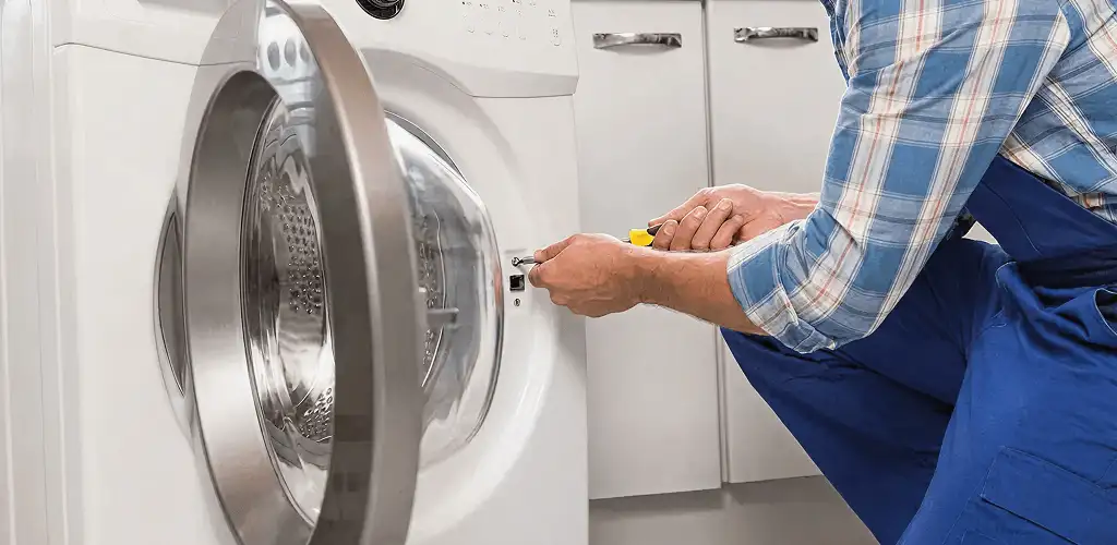 Handyman repairing a clothes dryer and checking electrical connections in St Paul, MN