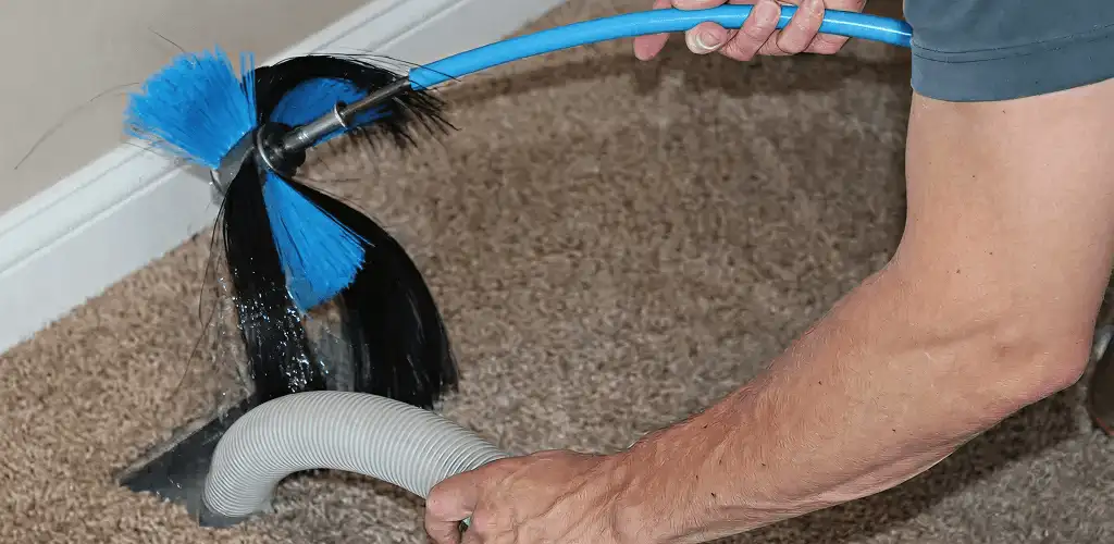 Dryer vent cleaning technician brushing lint from a vent line in St Paul, MN