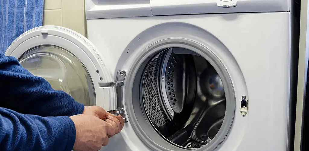 Washing machine repair handyman checking a front-load washer door and latch in St Paul, MN
