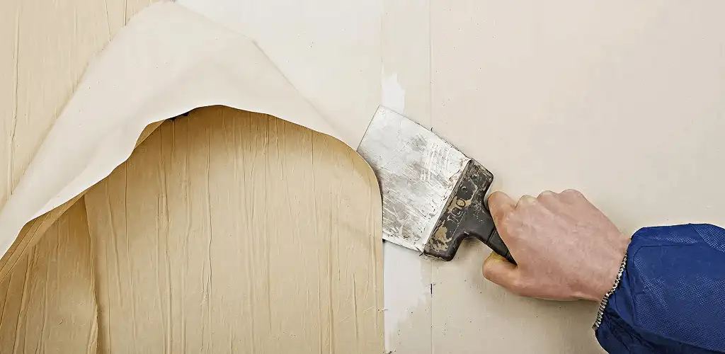 Handyman removing wallpaper with a scraper for wall preparation in St Paul, MN