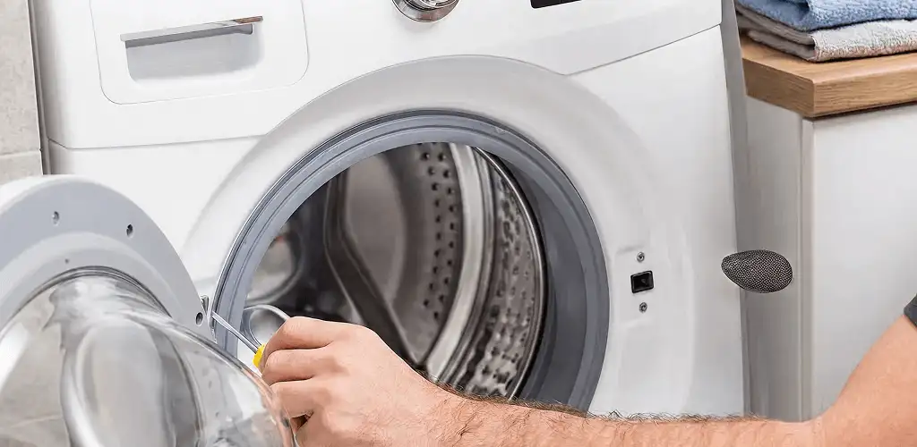 Handyman repairing a front-load washing machine and inspecting the drum in St Paul, MN