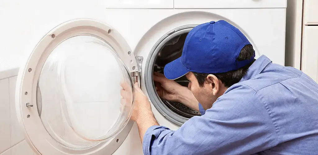 Washing machine repair handyman inspecting a front-load washer drum in St Paul, MN