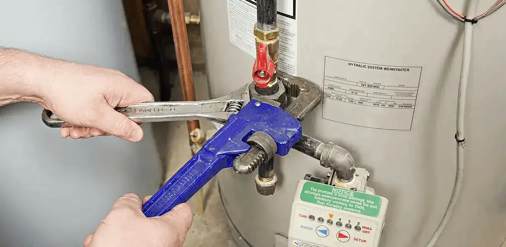 Water heater repair technician tightening the shutoff valve and supply line in St Paul, MN